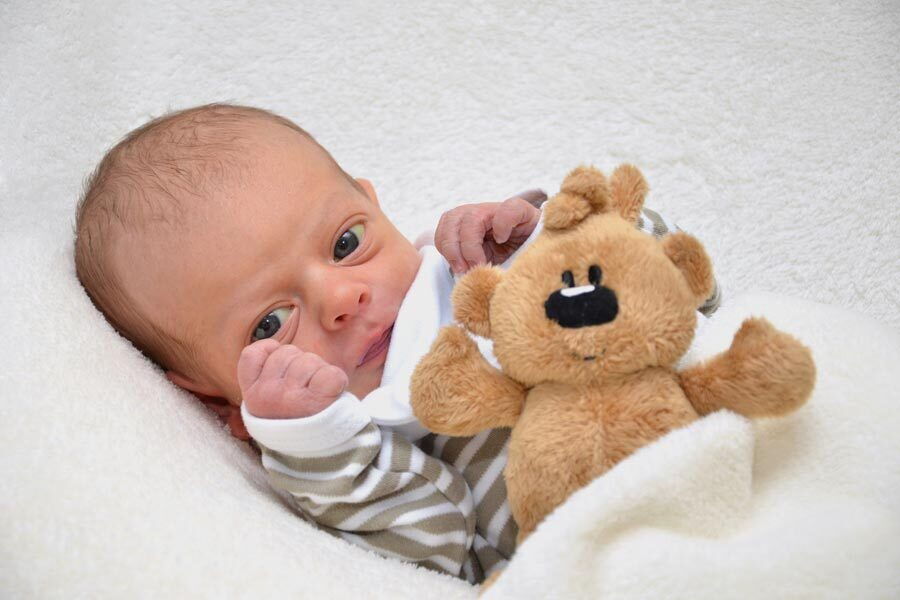 Il piccolo Erik Jonas sdraiato in una coperta con un orsacchiotto.