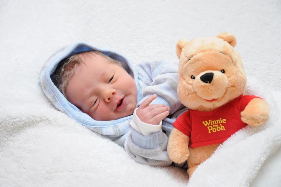 Il piccolo Jonas sdraiato su una coperta, avvolto in una giacca blu e coccolato dal peluche di Winnie the Pooh.