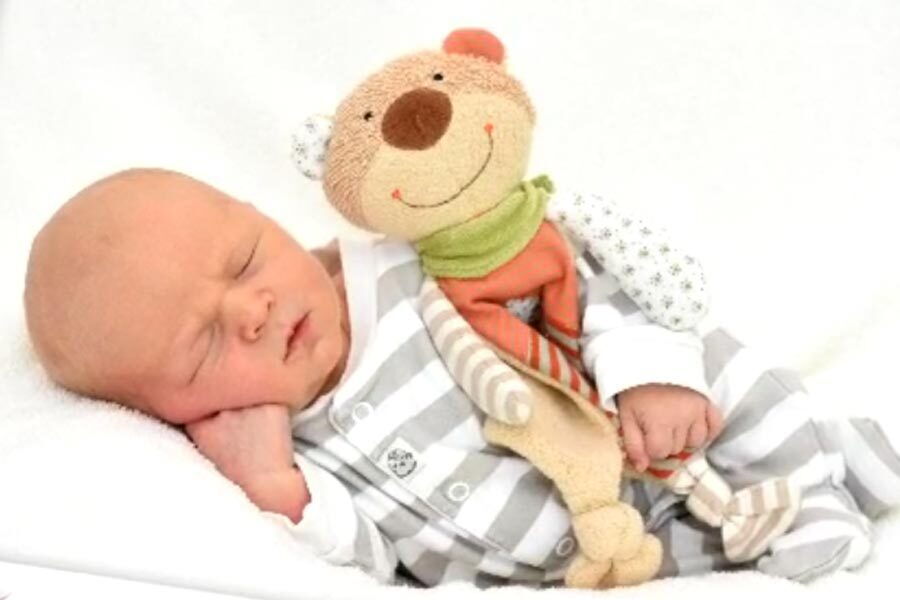 Il piccolo Luca dorme e tiene in braccio un orsacchiotto.