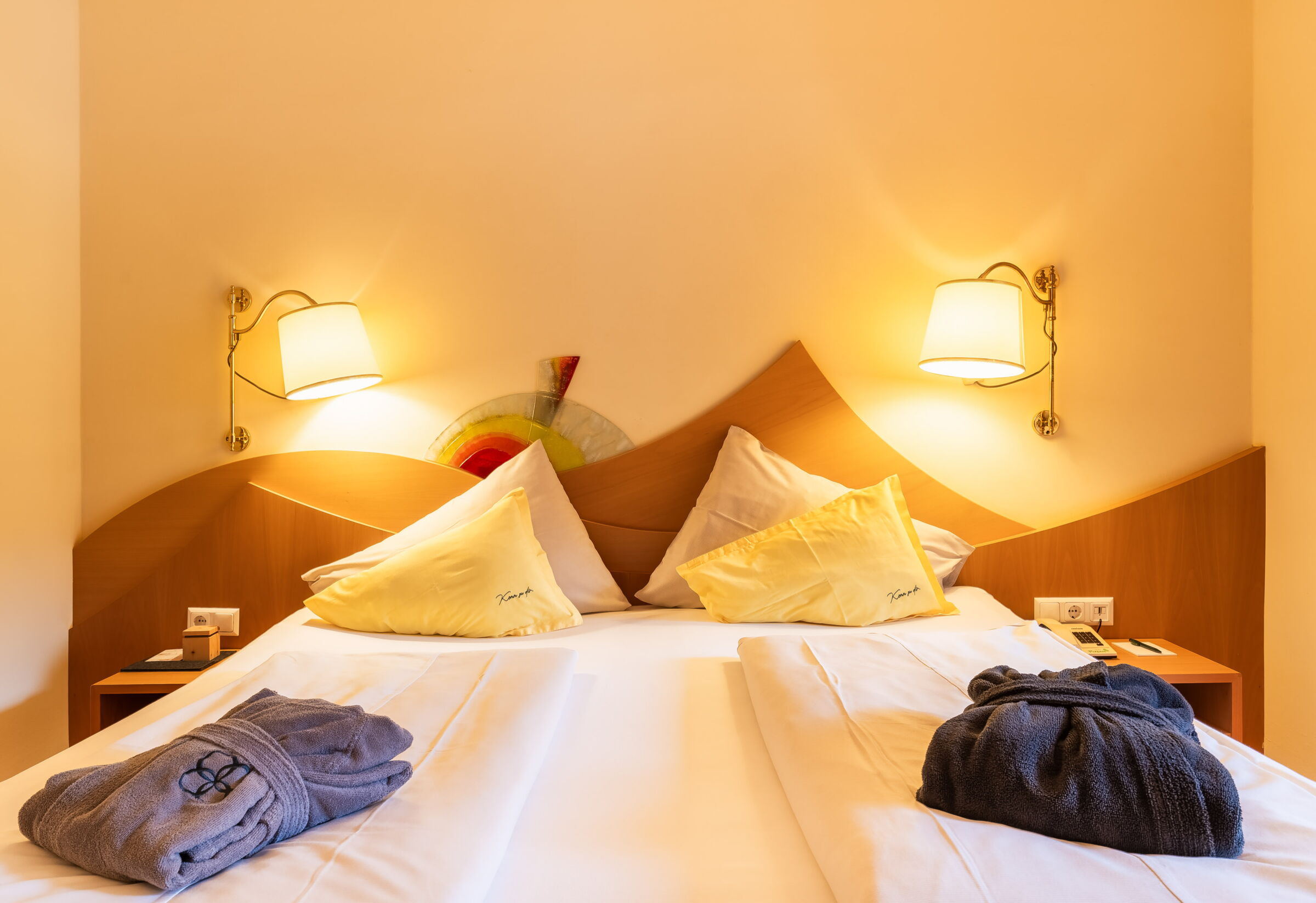 Gemütlicher Spa-Raum mit Bett, Kissen und Bademänteln für entspannende Momente in einem Hotelzimmer.