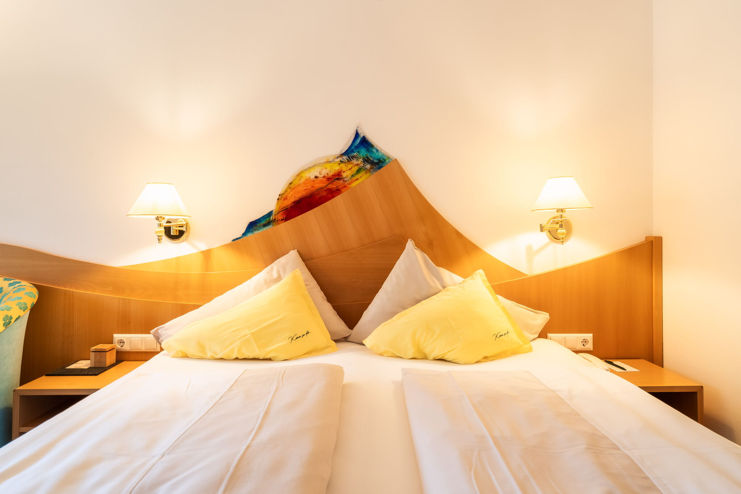 Gemütliches Zimmer mit einem Doppelbett und dekorativen Kissen in einem Wellnesshotel.