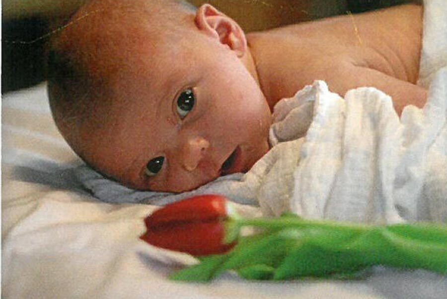 La piccola Sophie Elisa sdraiata su una coperta a pancia in giù con un fiore accanto a lei.