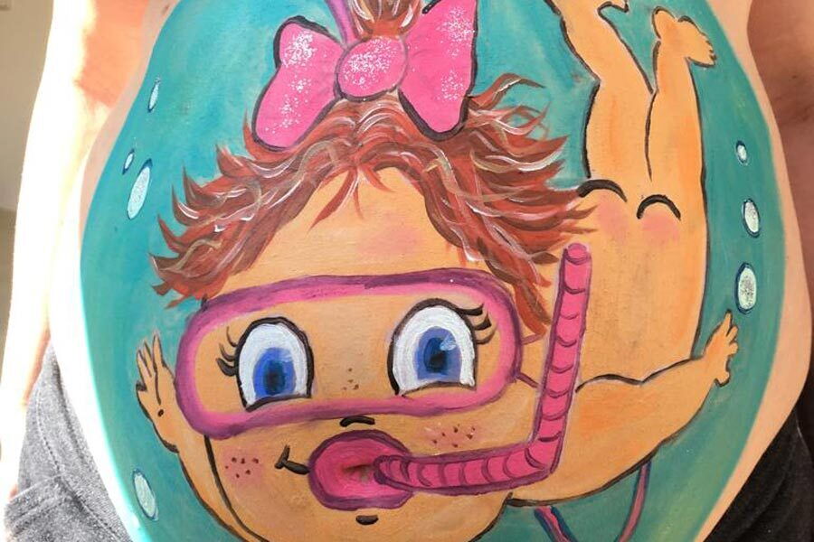 Ein Babybauch auf den ein Mädchen das taucht gemalt wurde.