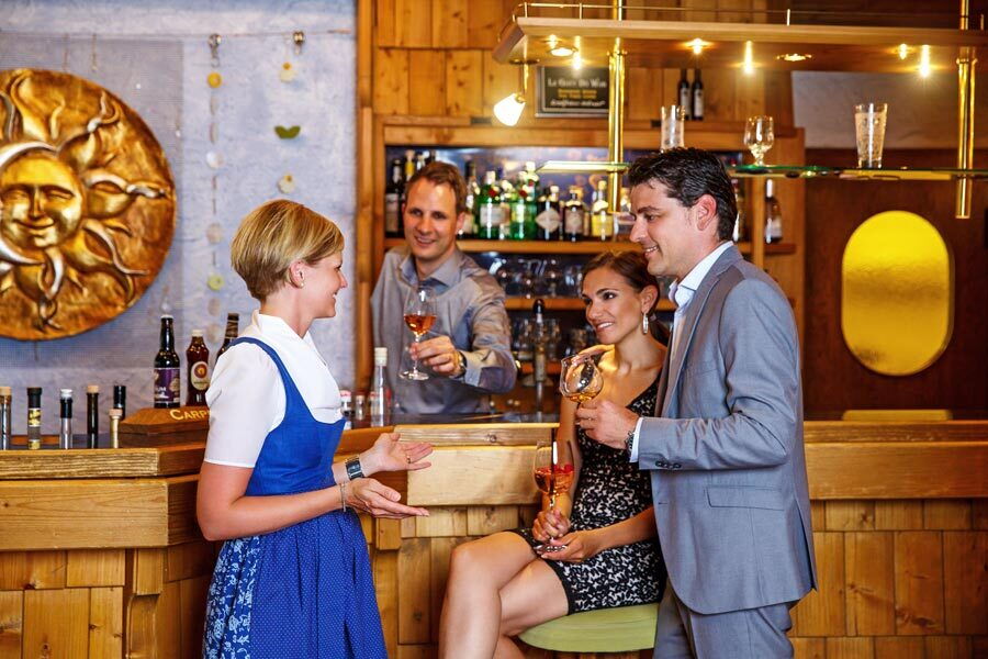 Interaktion zwischen Personal und Gästen an der Spa-Bar mit Getränken in der Hand.