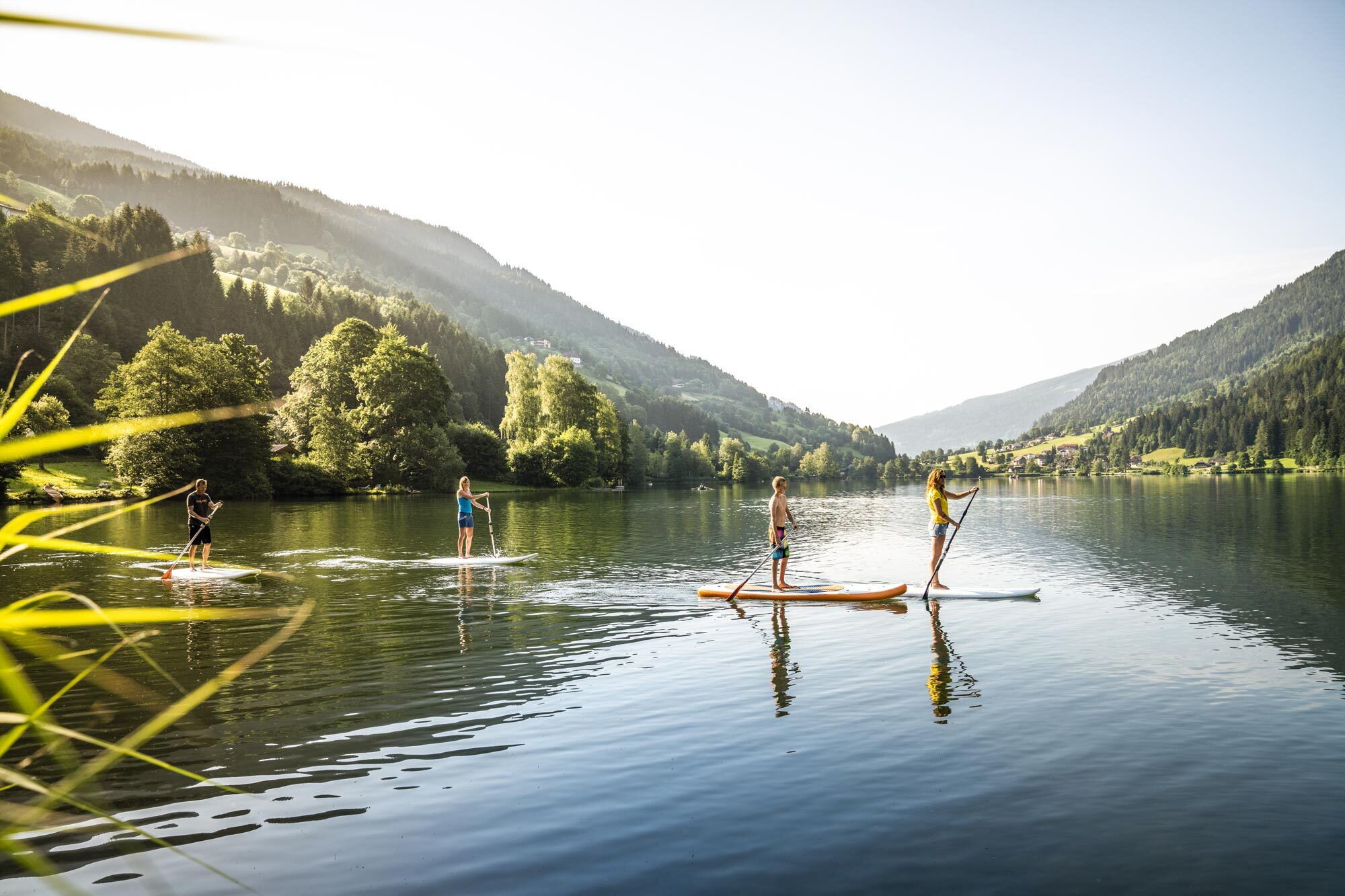 Personen paddeln auf einem ruhigen See inmitten der Natur und Berge der Umgebung
