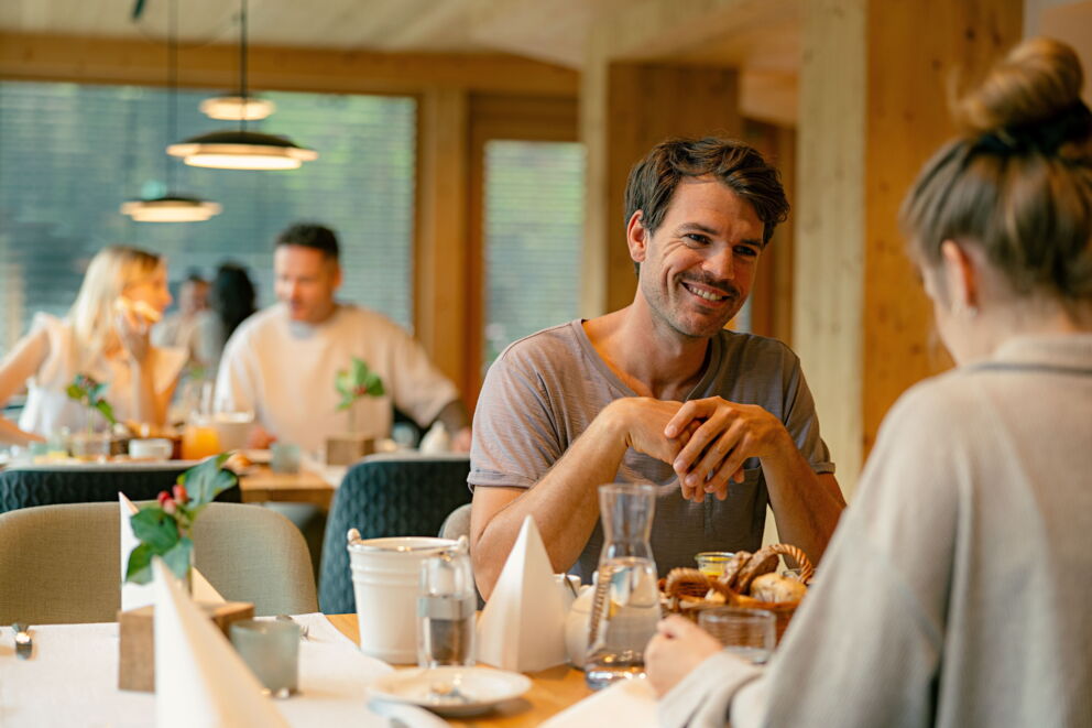 Ein Paar genießt ein gesundes Frühstück in einem Spa-Restaurant, umgeben von weiteren Gästen.