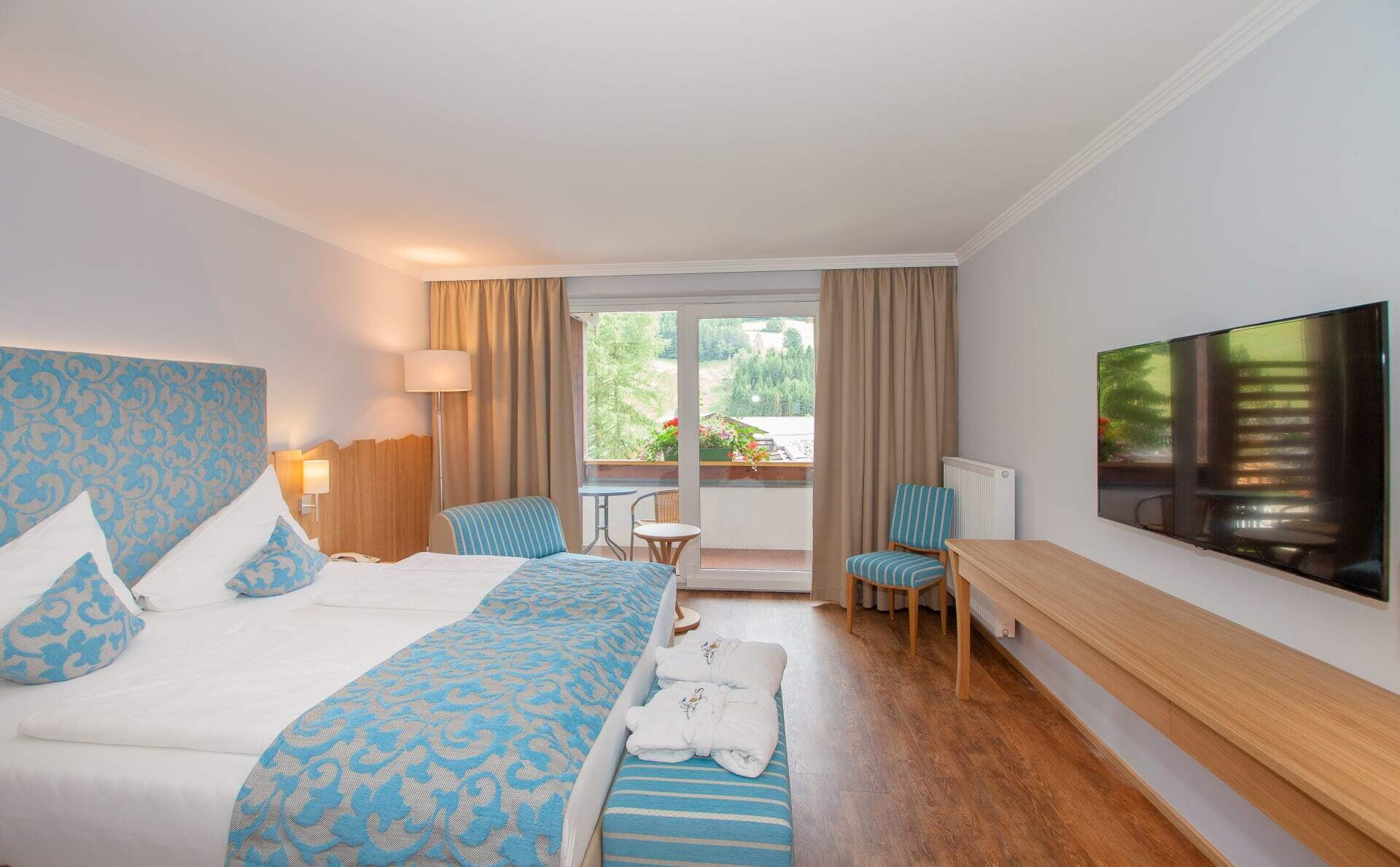 Gemütliches Hotelzimmer mit Doppelbett, Sitzecke und Balkon mit Aussicht auf die Umgebung.