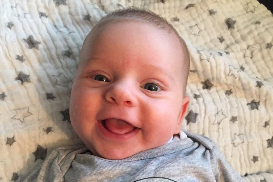 Il piccolo Peter sdraiato su una coperta e sorridente.