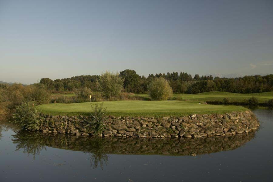 Landschaft mit Golfplatz umgeben von Wasser und üppiger Vegetation zur Förderung der Entspannung.
