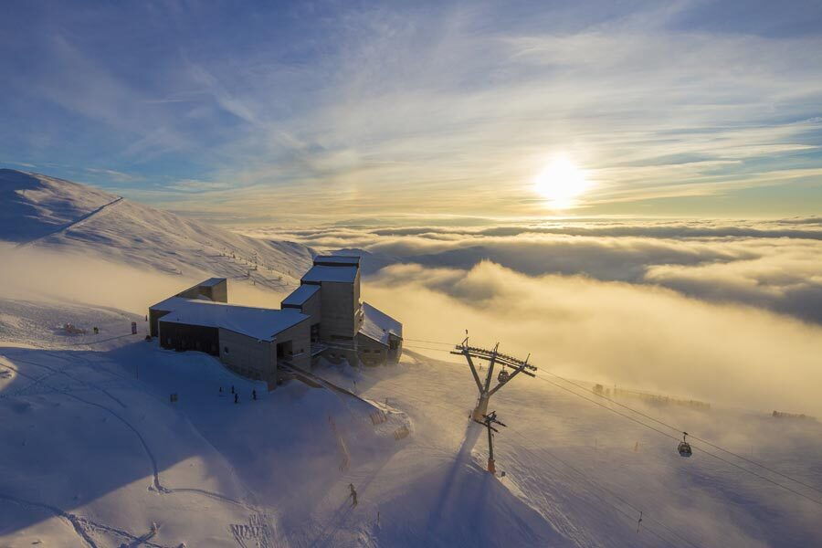 Moderne Architektur in einer verschneiten Berglandschaft mit einem Skilift und Sonnenuntergang