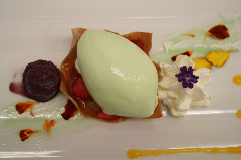 Elegantes Dessert mit grüner Mousse, frischen Erdbeeren und lila Sorbet für Gourmets