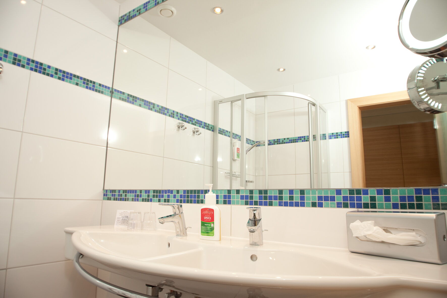 Modernes Spa-Badezimmer mit Waschbecken, Spiegel und Duschbereich, stilvoll gestaltet
