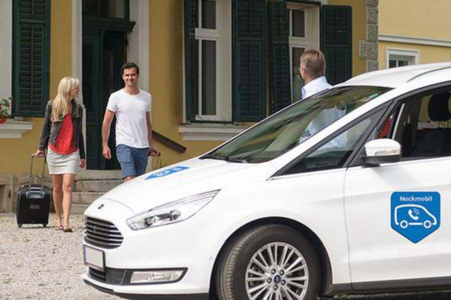 Ein Paar wird von einem Mitarbeiter am Fahrzeug in Empfang genommen und zum Spa gebracht.