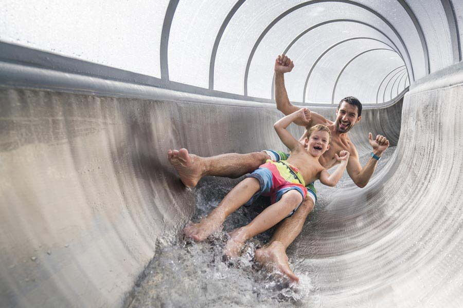 Ein Mann und ein Kind genießen den Spaß auf einer Wasserrutsche im Freizeitbereich.