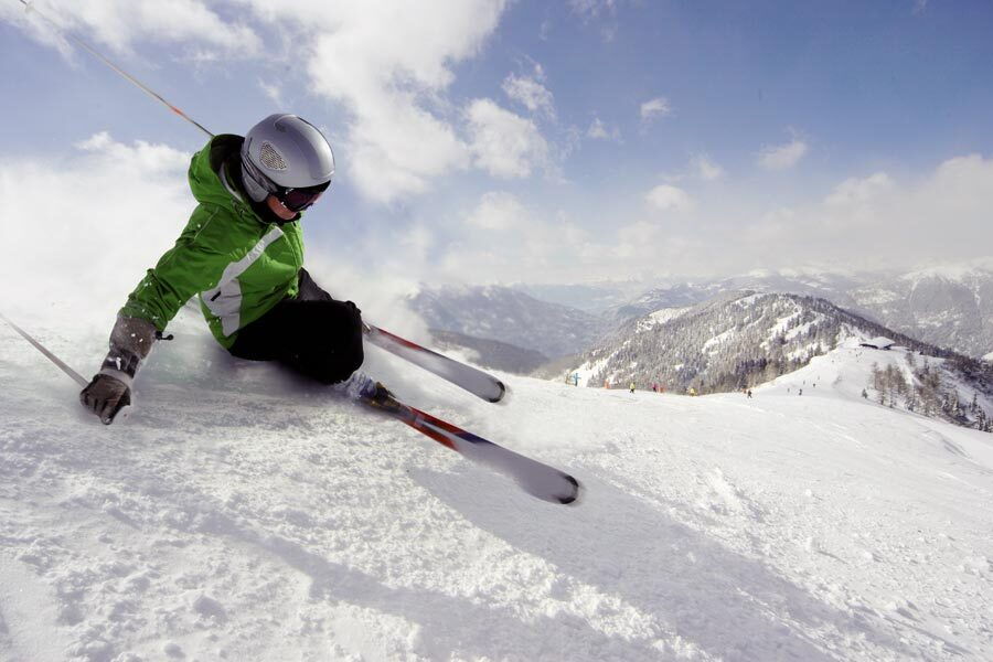 Skiers skiing down a piste in a snowy winter landscape in Carinthia