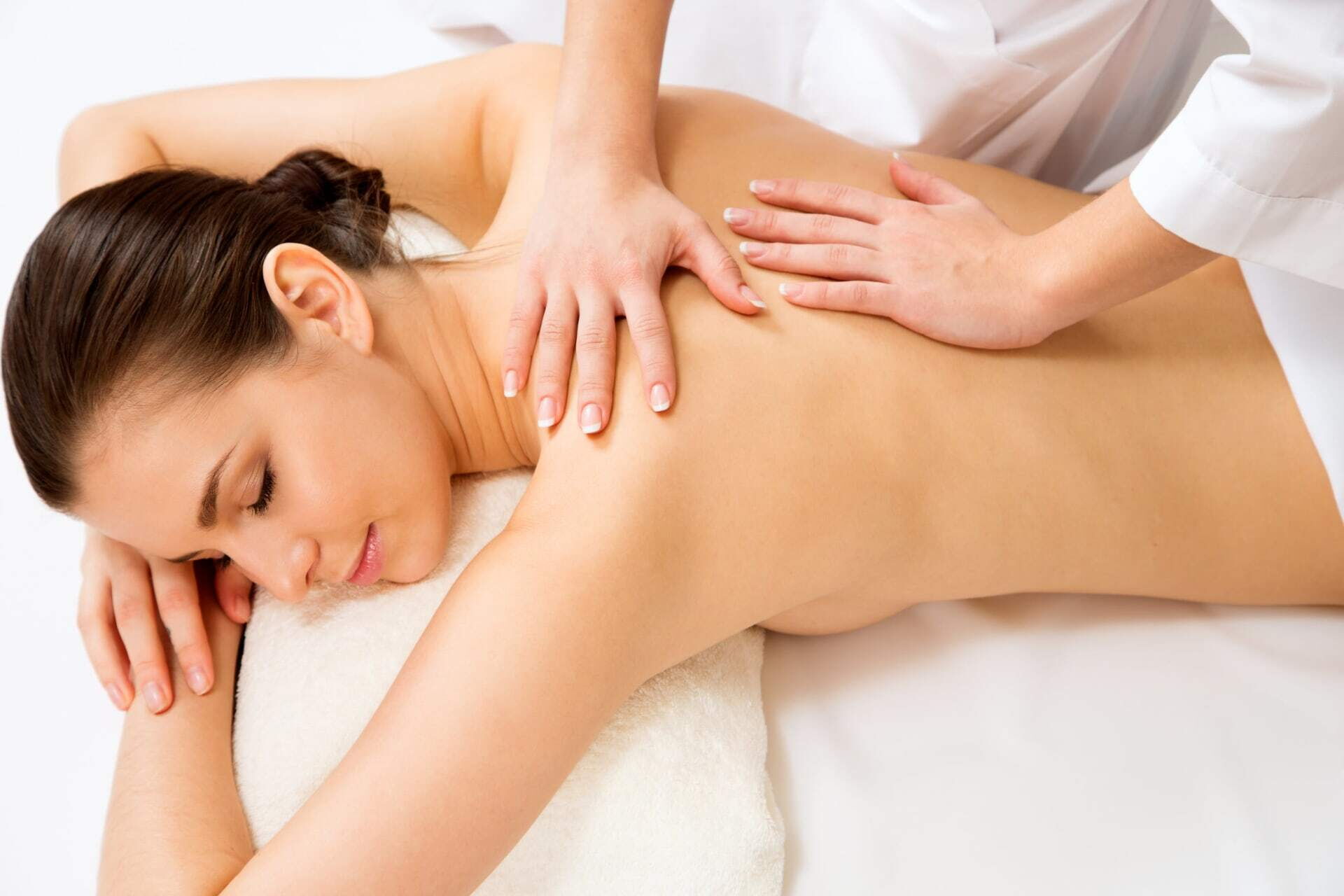 Eine Frau liegt auf einem Massagetisch und erhält eine Rückenmassage von einer Therapeutin.