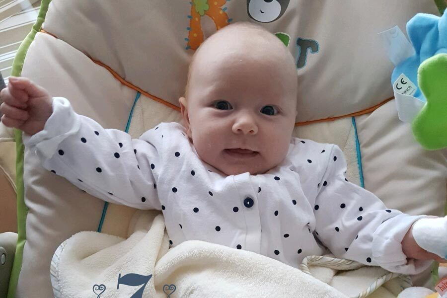 La piccola Isabella Stefanie è sdraiata su un tappeto da gioco e sorride.