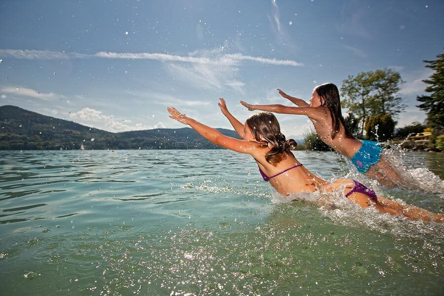 Children jumping into a crystal-clear lake in beautiful Carinthia.