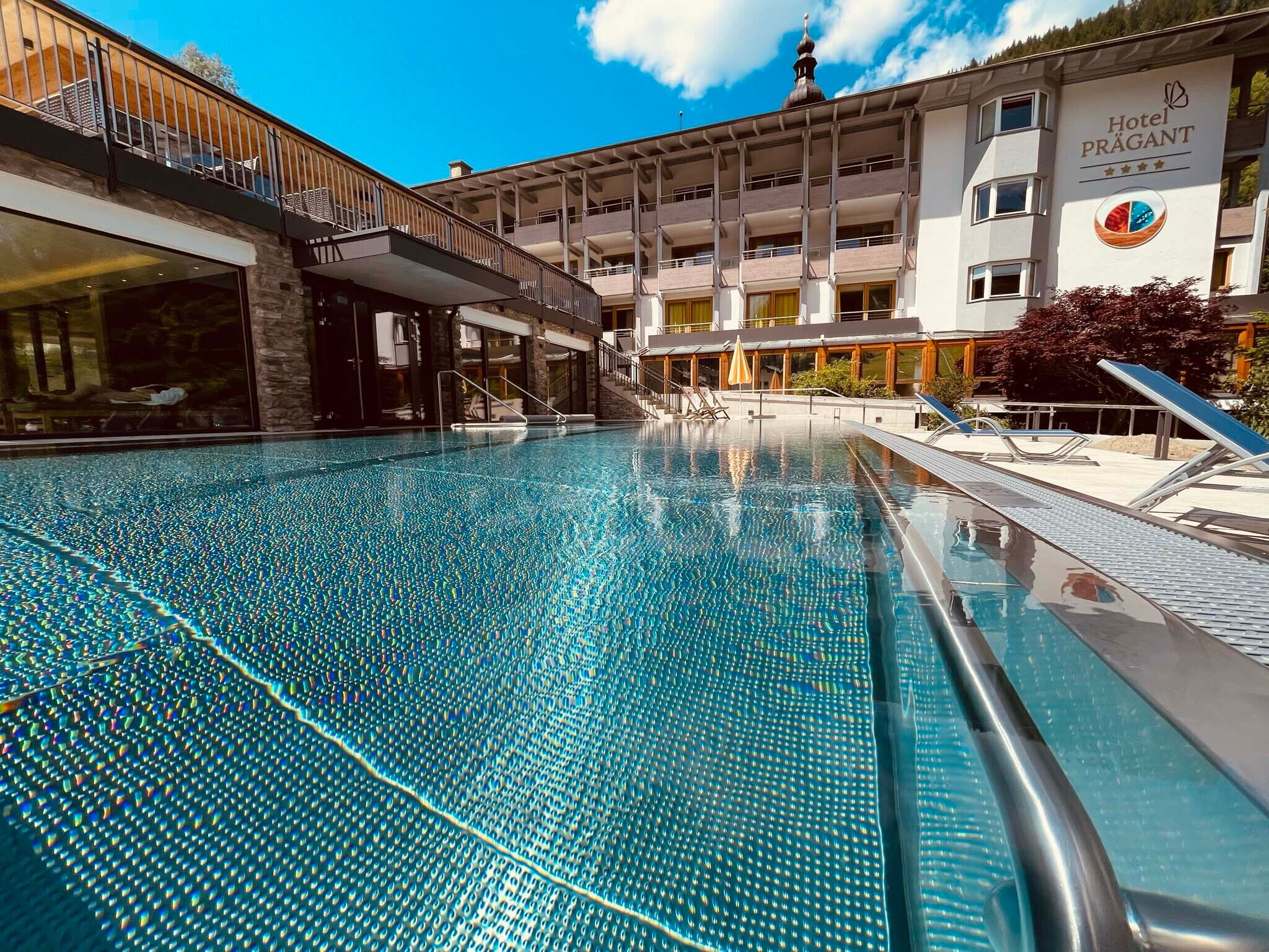 Modernes Hotel mit Schwimmbecken und Liegen in einer ruhigen Umgebung für Entspannung.