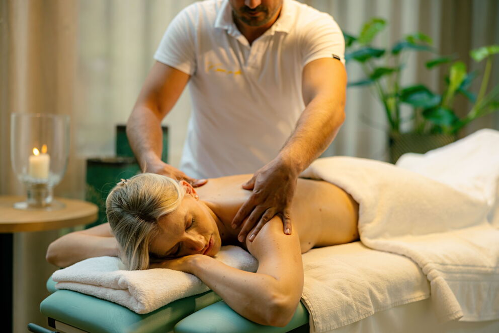 Therapeut bei der Massage eines Kunden in einem entspannenden Spa-Umfeld mit beruhigender Dekoration