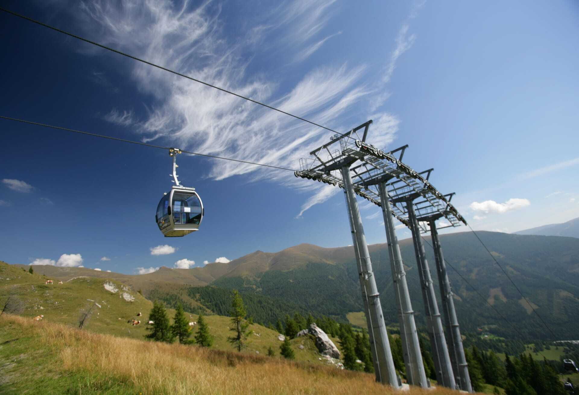 Kabinenbahn fährt über eine Berglandschaft unter klarem Himmel mit sanften Hügeln im Hintergrund