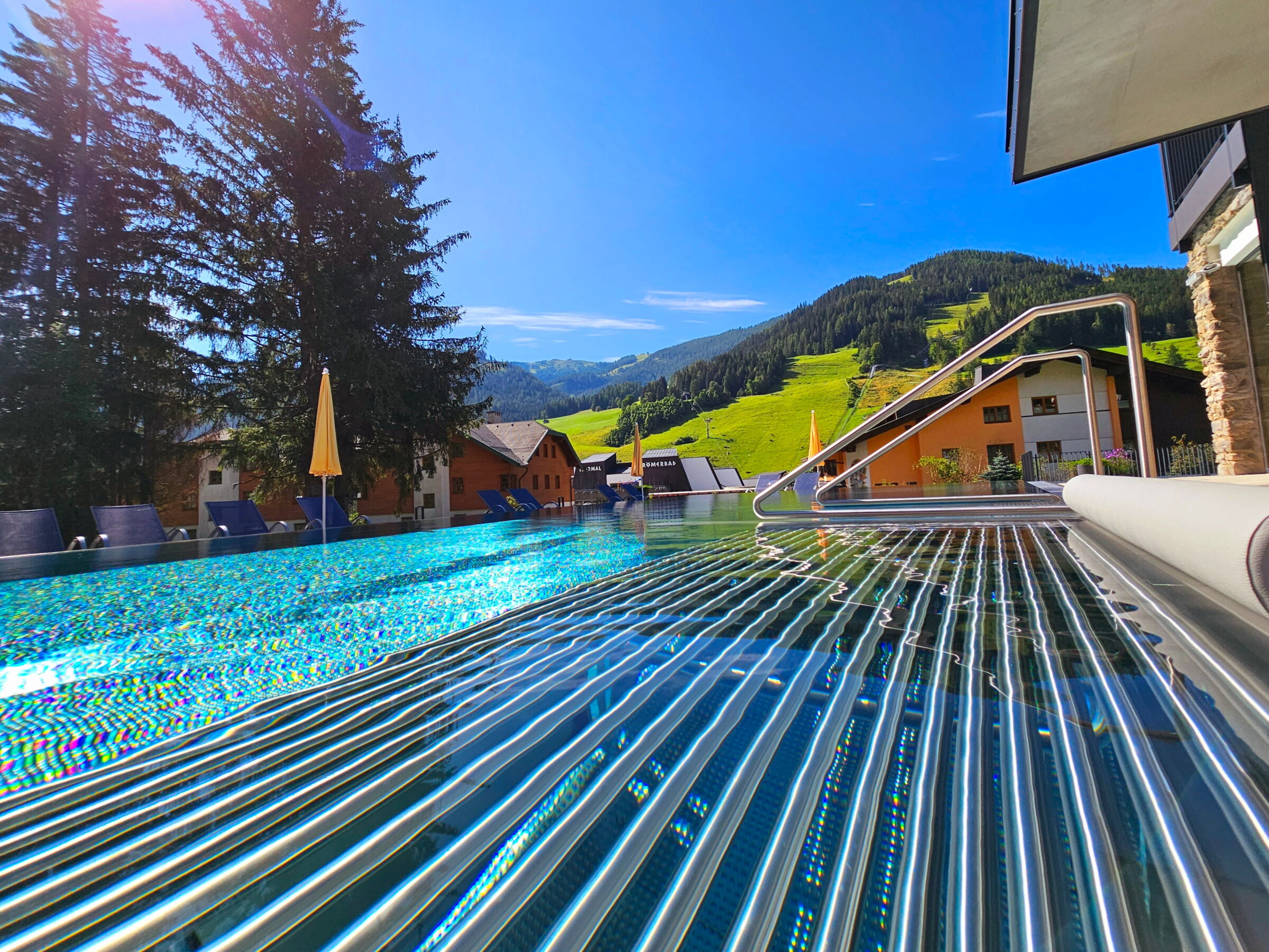 Außenpool inmitten einer grünen Berglandschaft unter blauem Himmel für erholsame Momente