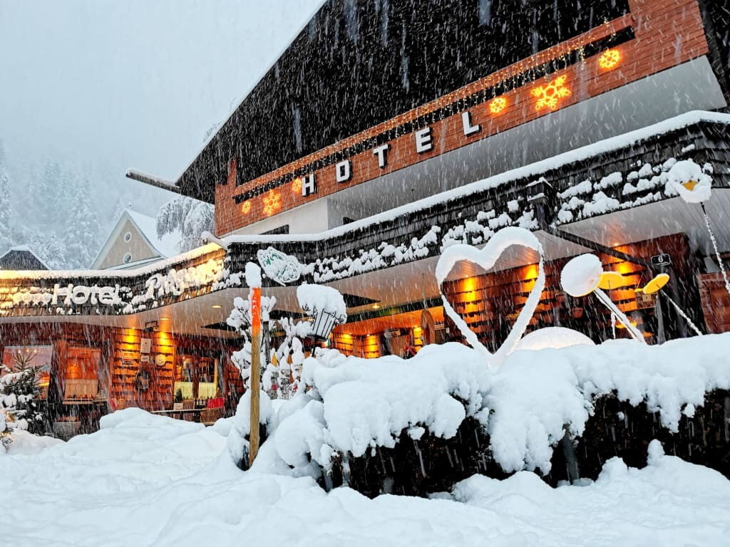 Hotelgebäude im Schnee mit dekorativen Elementen im Vordergrund und starkem Schneefall