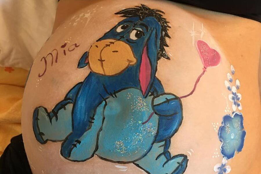 Ein Babybauch auf den ein Esel gemalt wurden.