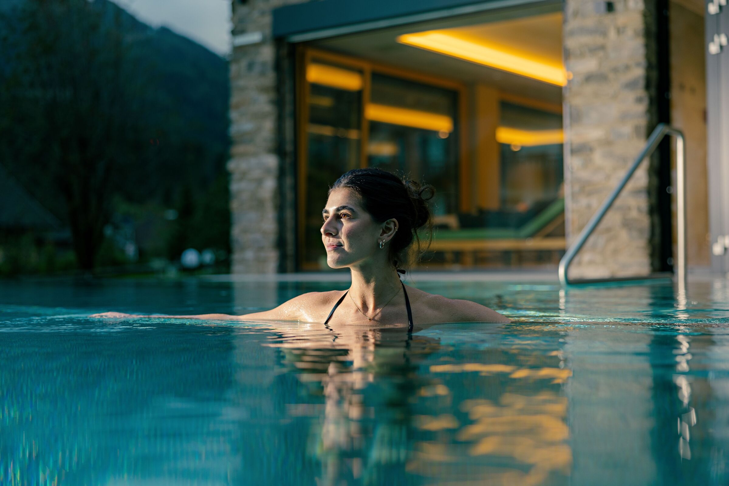 Frau entspannt in einem Schwimmbad eines modernen Spas mit ruhiger Ausstrahlung.