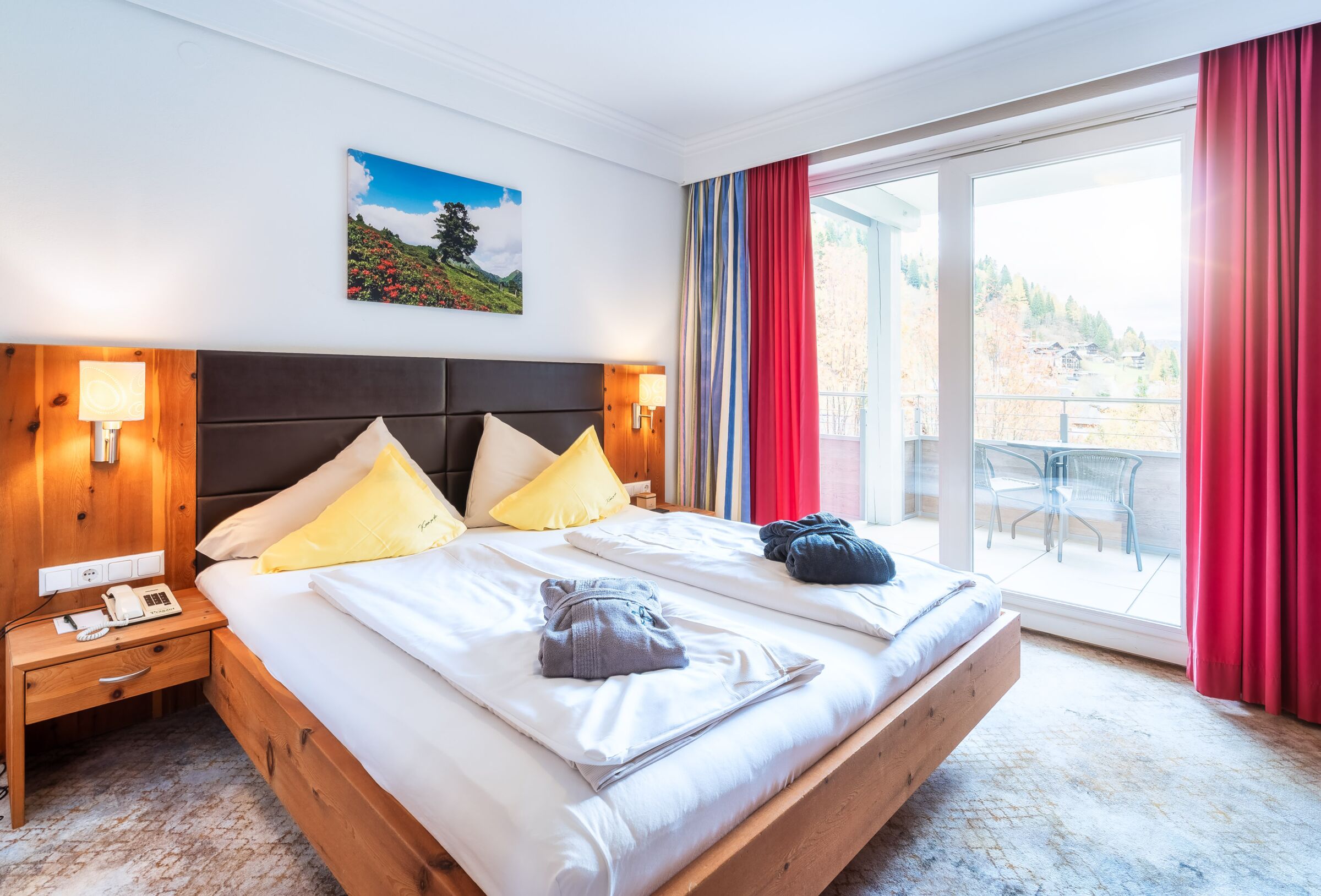 Spa Raum mit Doppelbett, Holztisch und Balkon mit Blick auf die Natur für Erholungssuchende.