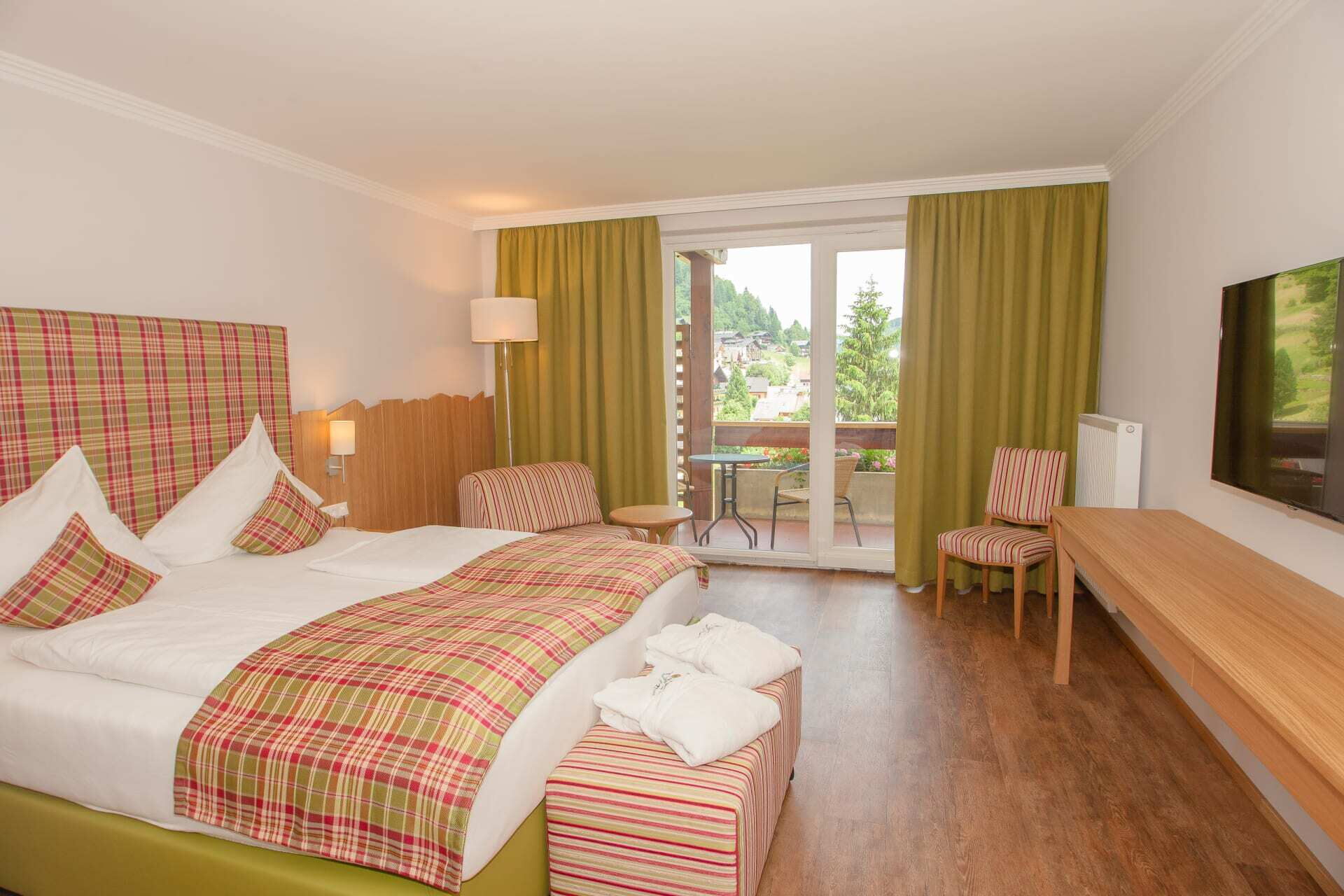 Helles Hotelzimmer mit Doppelbett, Sitzbereich und großen Fenstern zur Aussicht.