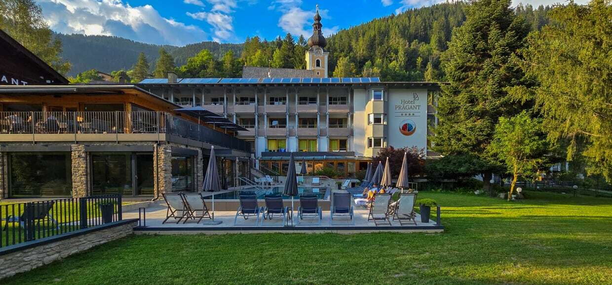 Hotelgebäude in den Bergen mit einem Außenpool und einem gestalteten Gartenbereich