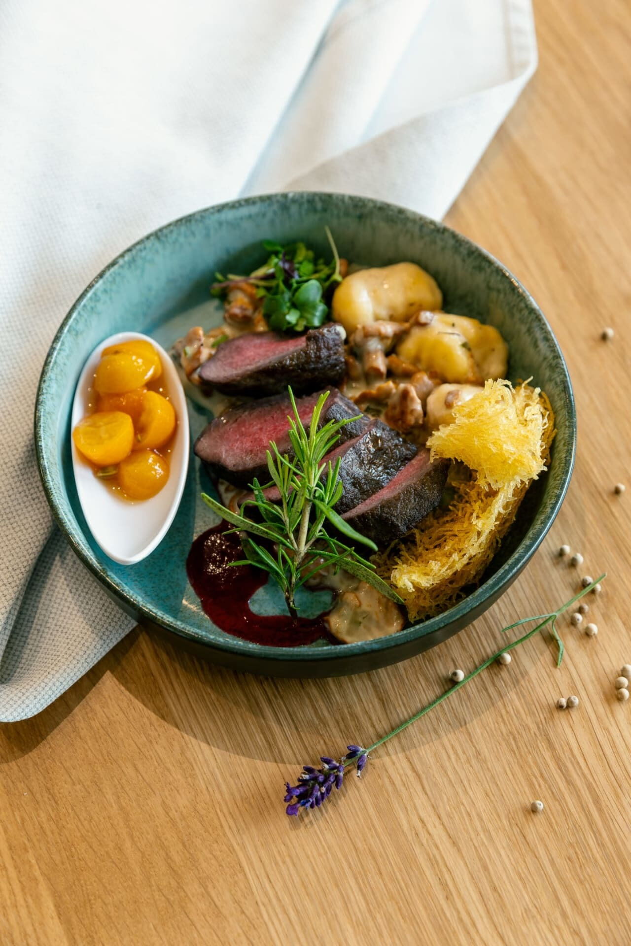 Gourmetgericht mit kunstvoll geschnittenem Fleisch und Beilagen, dekoriert mit Kräutern