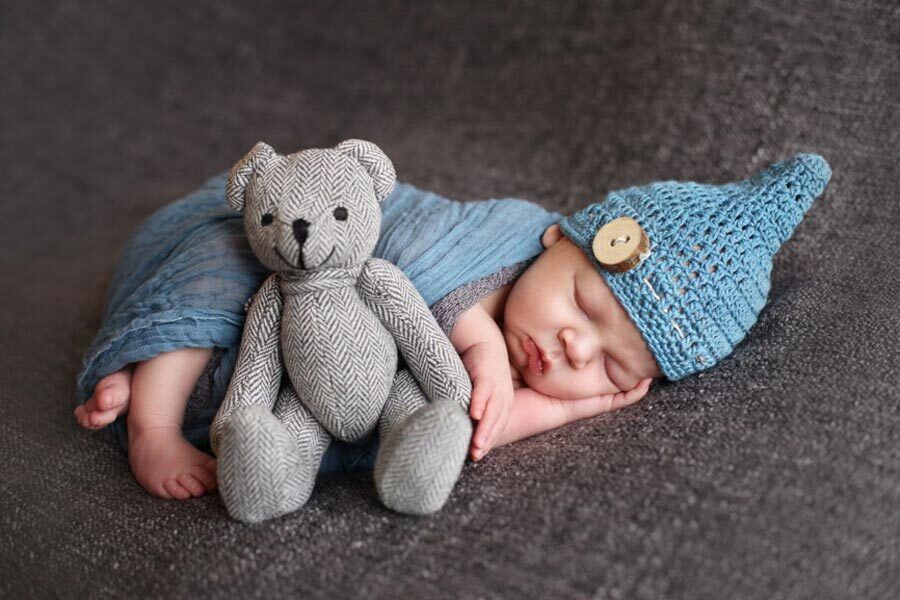 Baby Stephan sleeping with a teddy bear lying next to him.