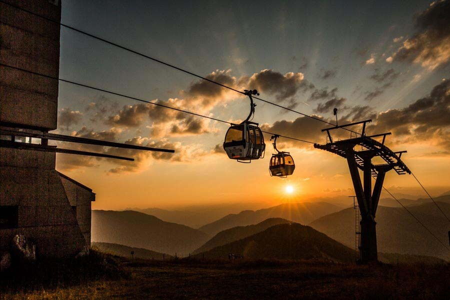 Aussicht auf Berge mit Bergbahn und Seilbahn im Sonnenuntergang, ideal für Wellnessurlaub.