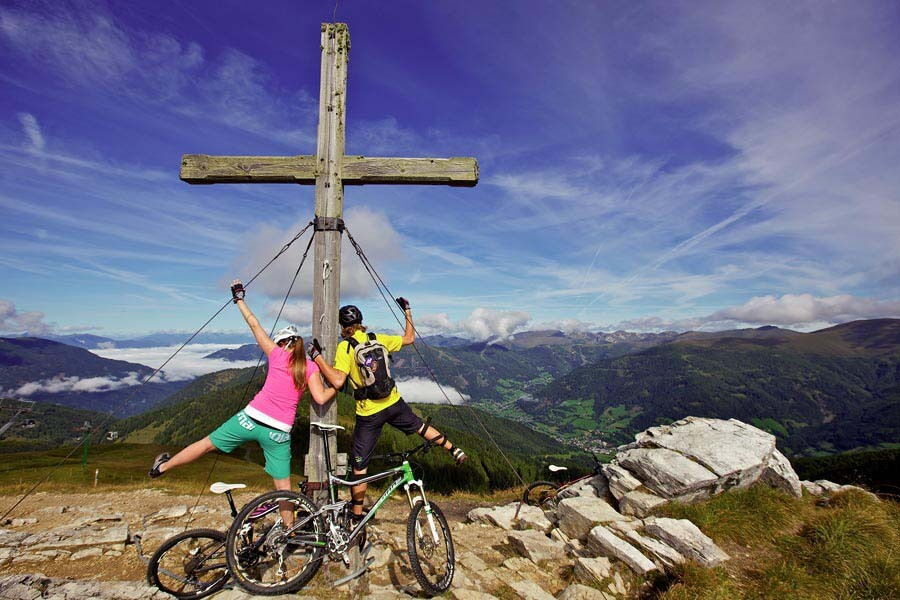 Two mountain bikers next to the summit cross in Bad Kleinkirchheim