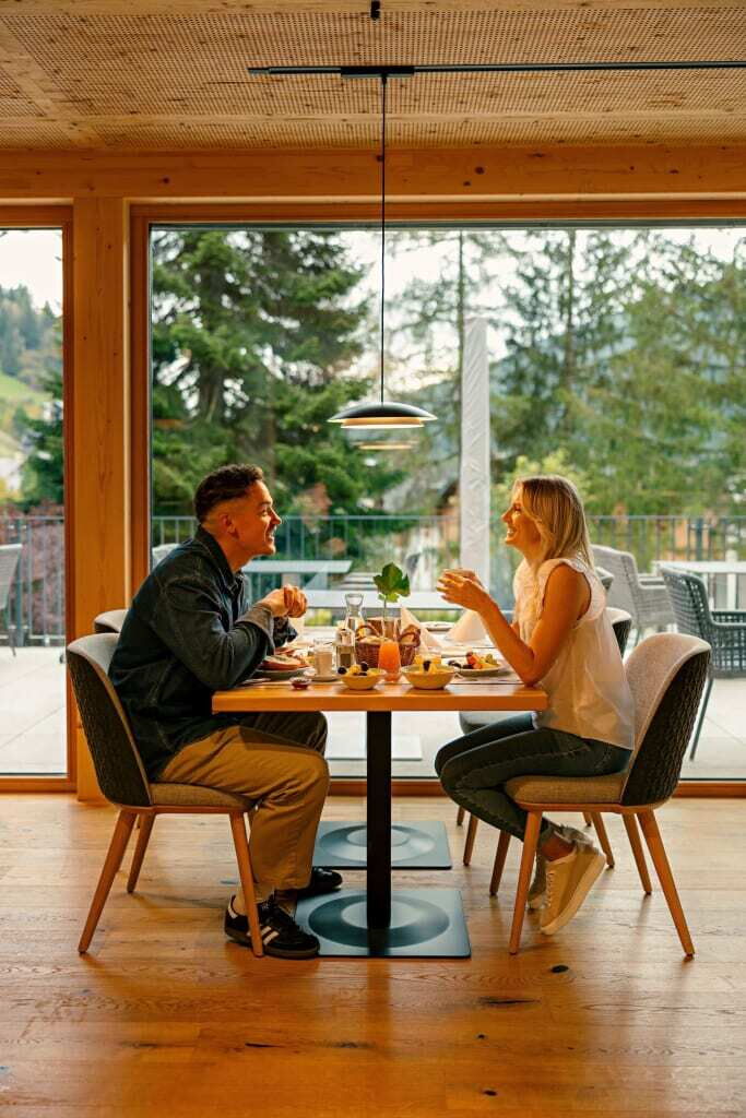 Ein Paar genießt ein romantisches Abendessen in einem modernen Restaurant mit großen Fenstern.