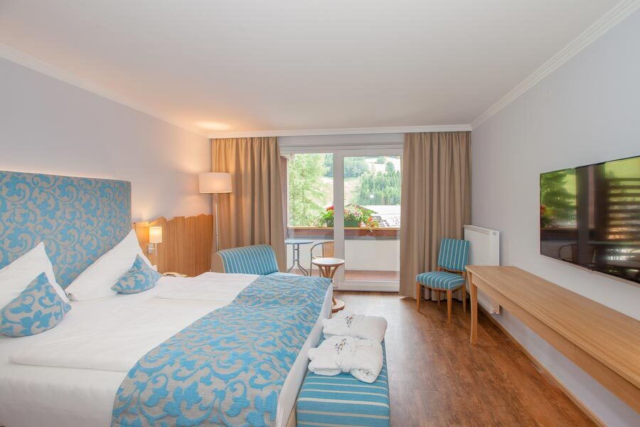 Spa-Raum mit Bett, dekorativen Kissen und Sitzbereich auf Balkon mit Ausblick zur Erholung.