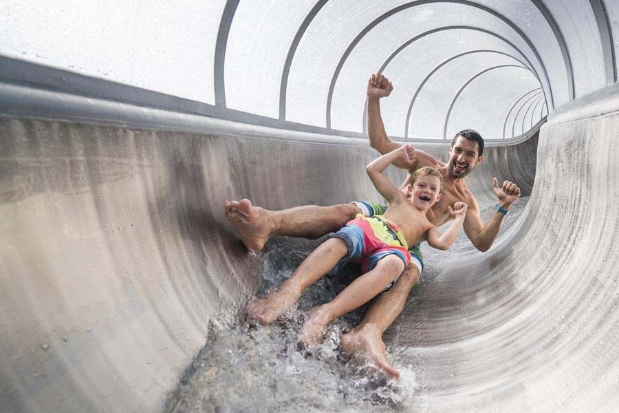 Ein Mann und ein Kind genießen den Spaß auf einer Wasserrutsche im Freizeitbereich.