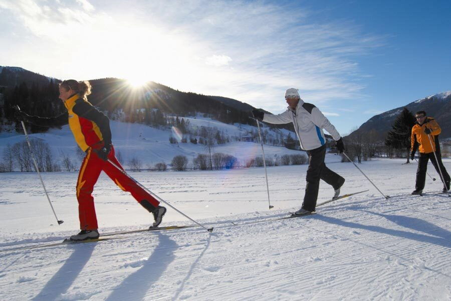Three cross-country skiers in a snowy winter landscape in Carinthia