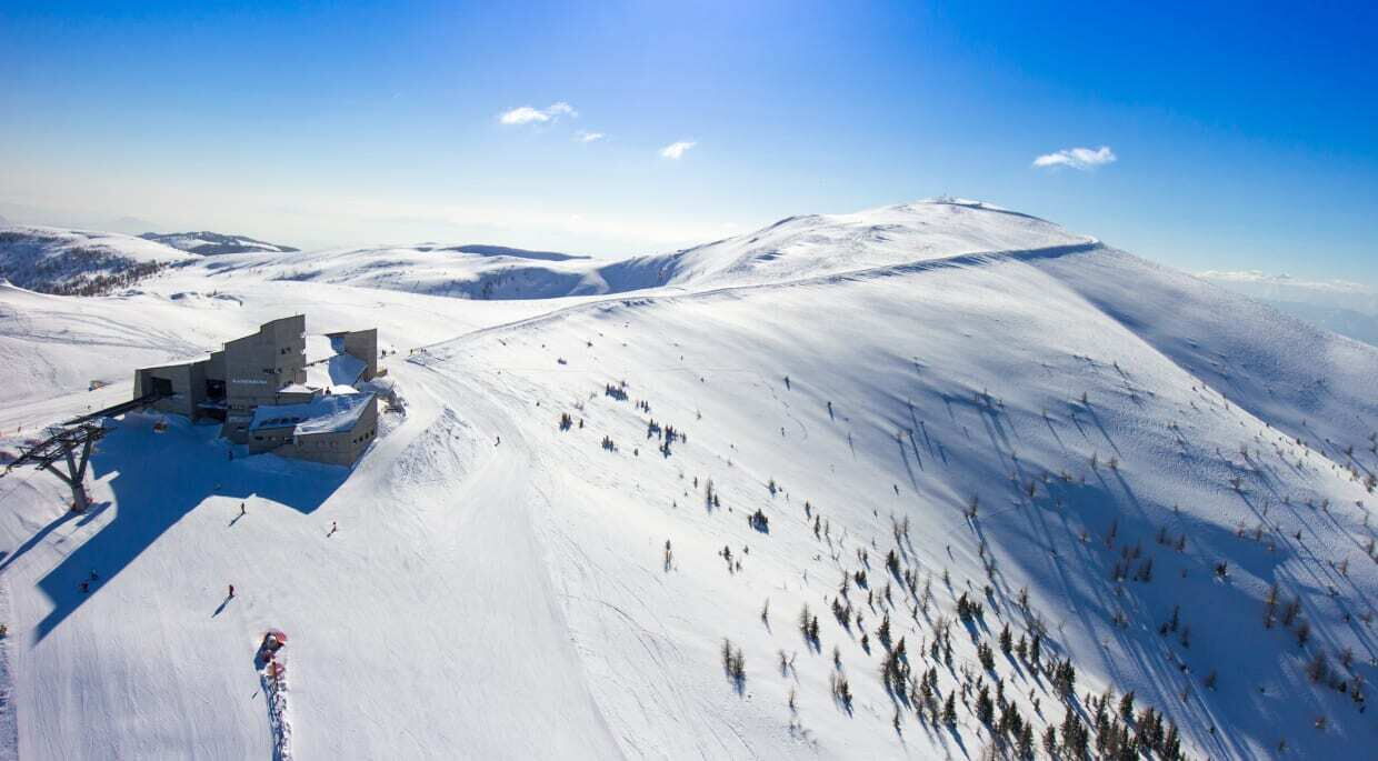 Skigebiet mit schneebedeckten Bergen und klarem blauen Himmel, ideal für Wintersport.