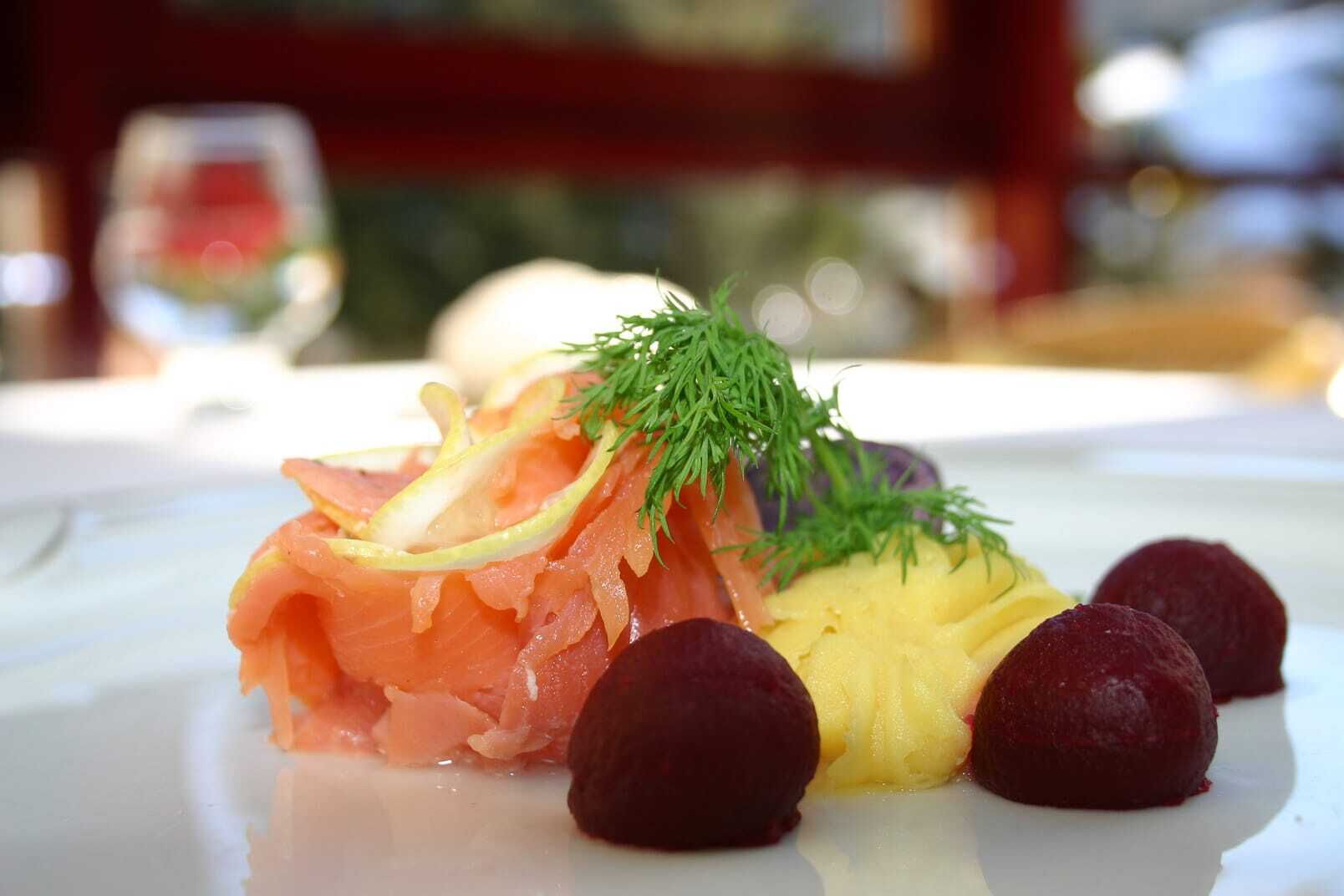 Ein Gourmetgericht mit Räucherlachs, Dill, Kartoffelbrei und Rote Beete auf einem Teller.