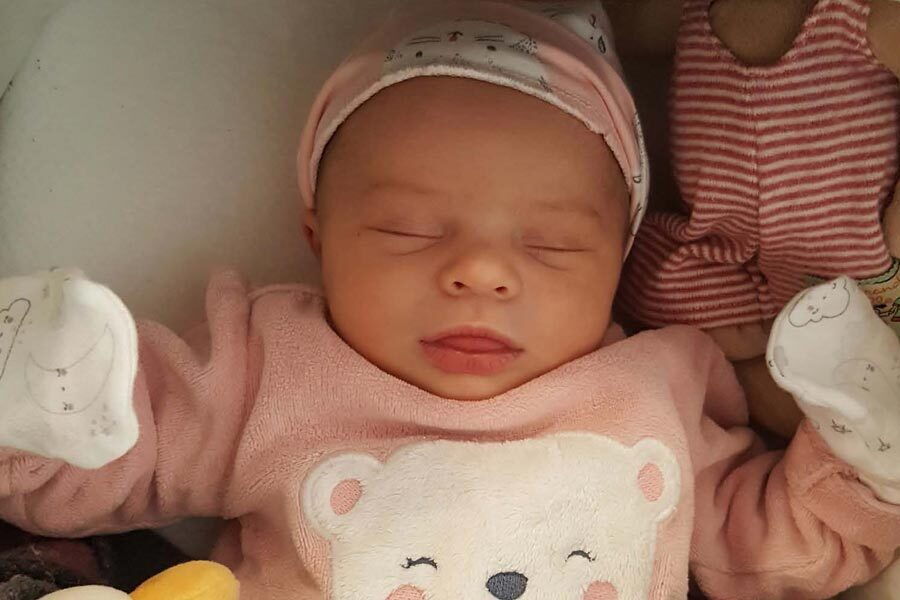 La piccola Camille dorme e indossa un maglione rosa con un orsetto.