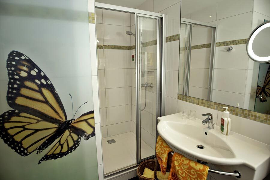Ein elegantes Badezimmer mit Dusche und einem dekorativen Schmetterling-Motiv an der Wand