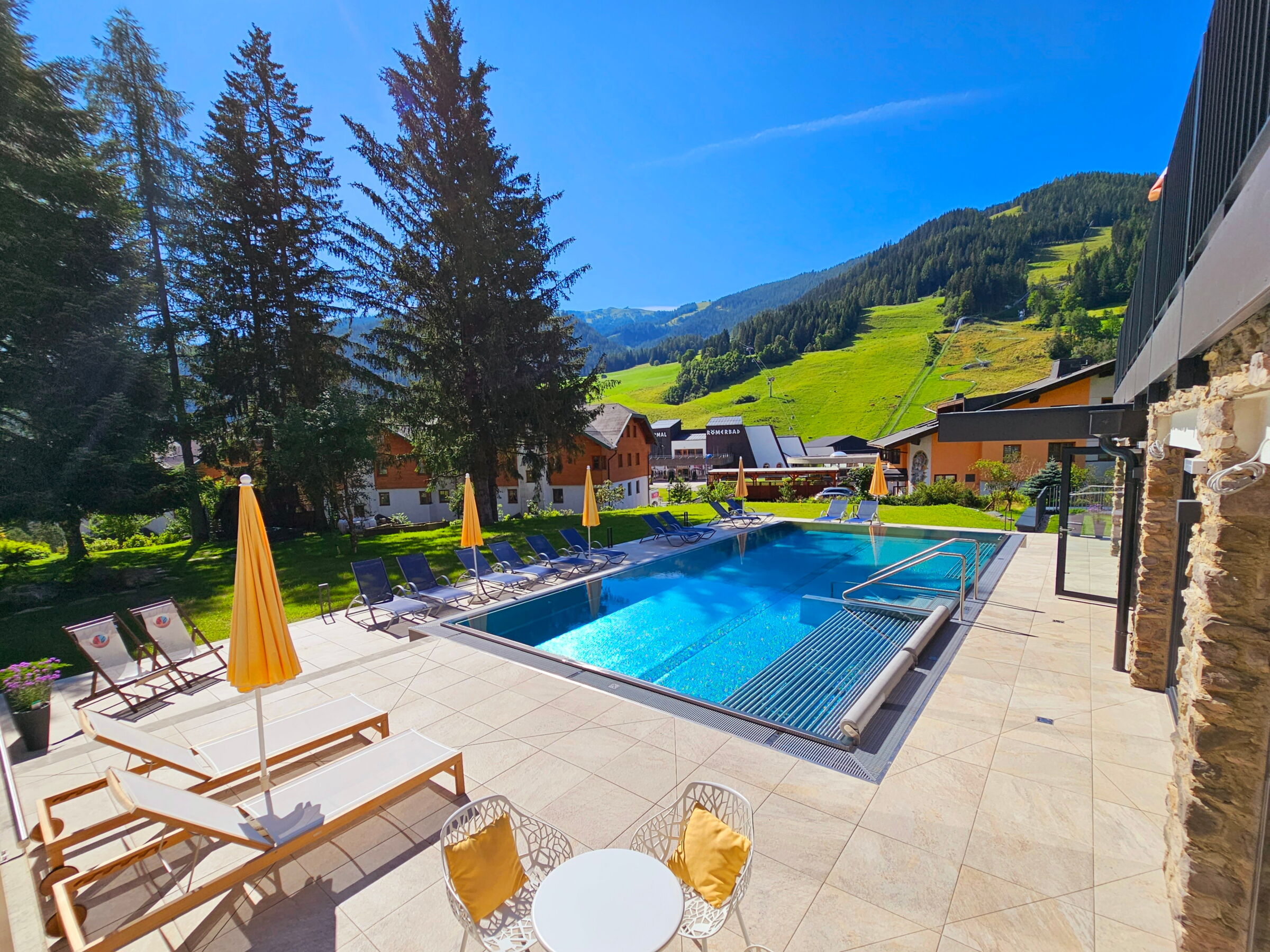 Freiluft-Wellnessbereich mit Schwimmbecken, Liegen und Bergblick für erholsame Stunden