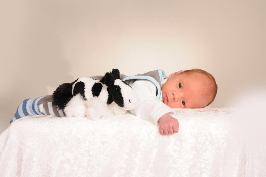 Il piccolo Fabian Johannes è sdraiato sulla pancia su una coperta con un peluche.
