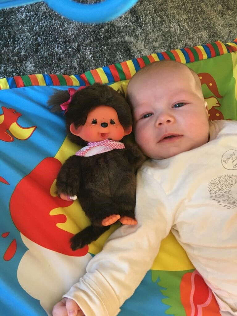 Baby Helena sdraiata su un tappeto da gioco con un peluche.