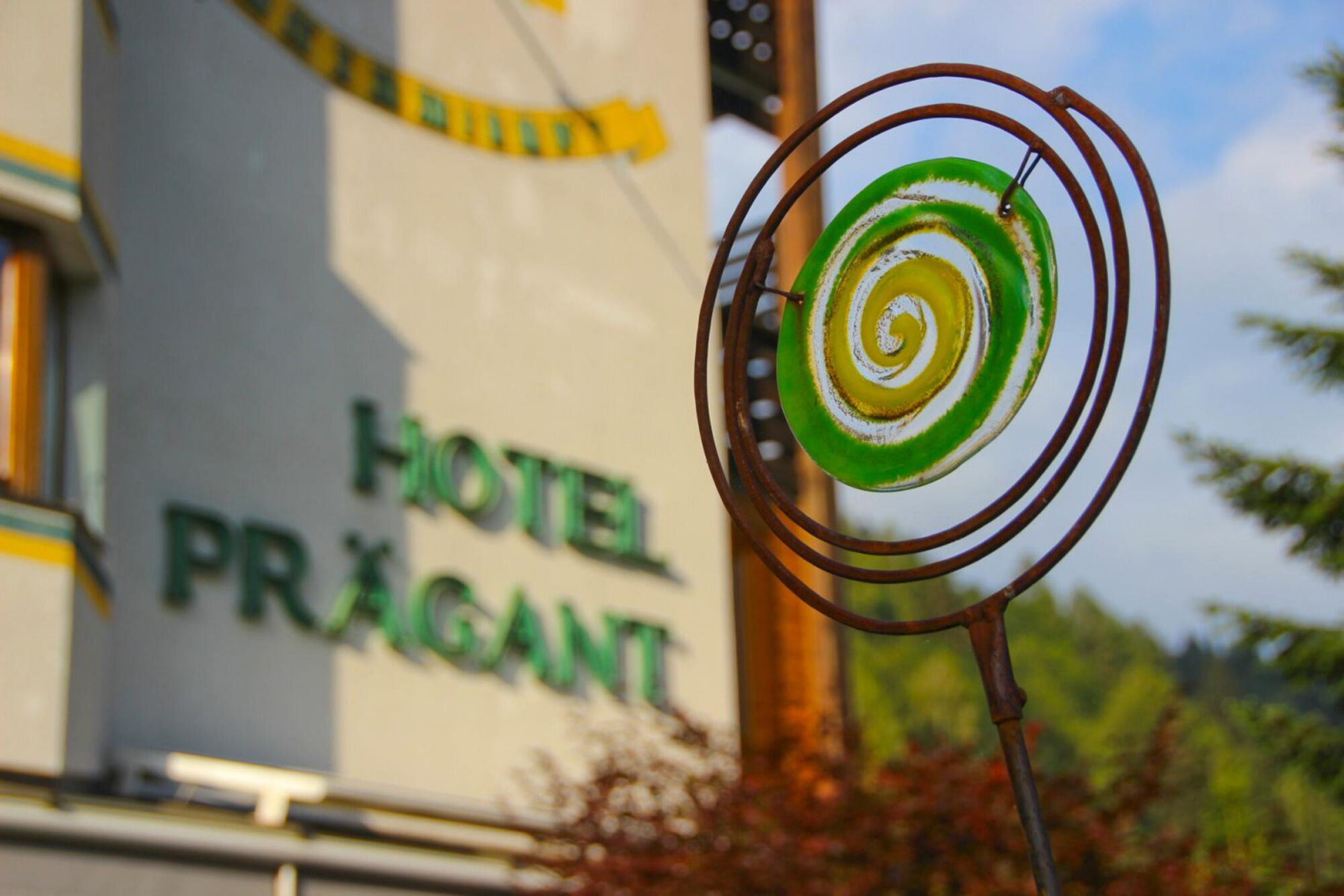 Dekorative Spiralskulptur im Vordergrund mit dem Hotel Prägant im Hintergrund sichtbar