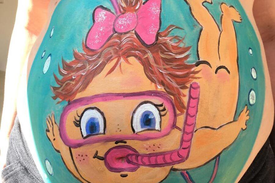 Ein Babybauch auf den ein Mädchen das taucht gemalt wurde.
