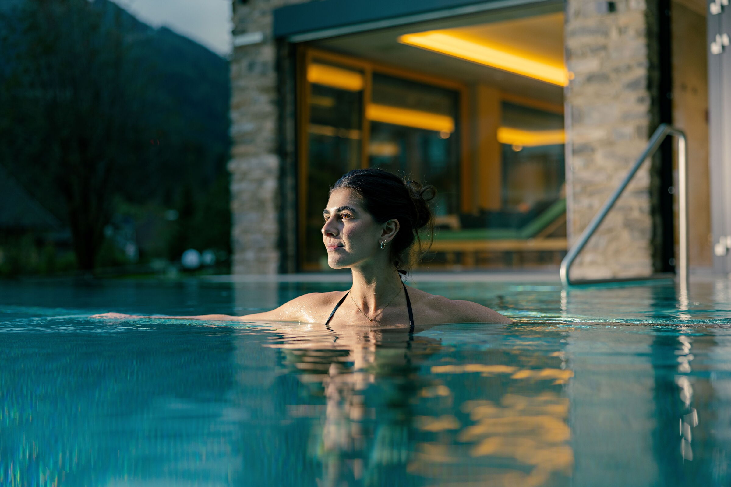 Frau entspannt in einem Schwimmbad eines modernen Spas mit ruhiger Ausstrahlung.